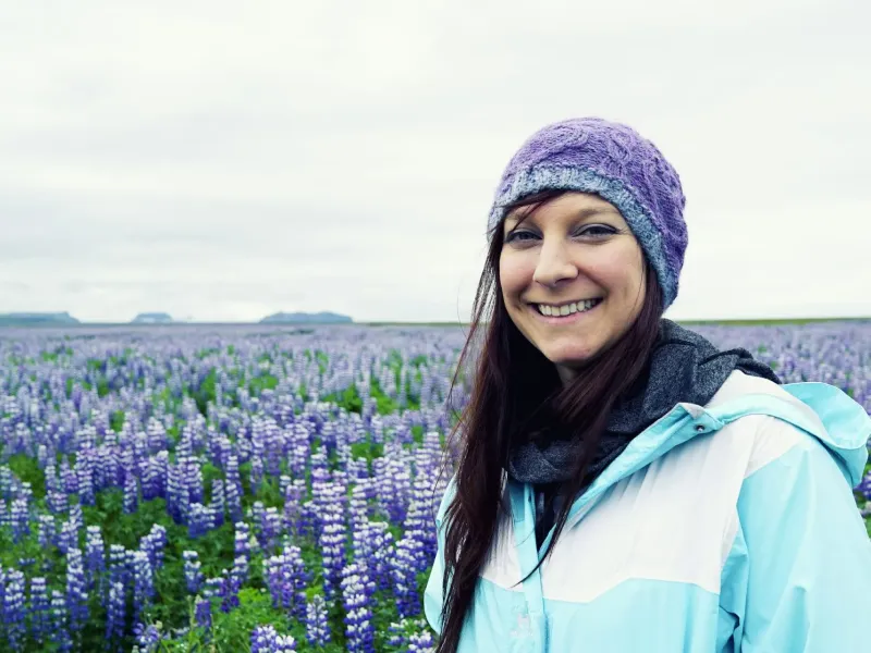 Emily Backes smiling in a lupine field in Iceland